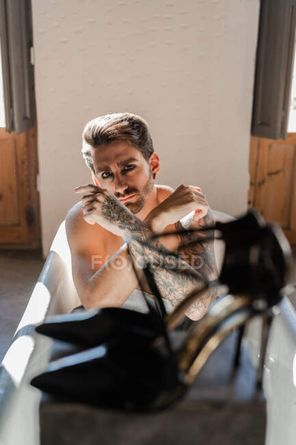 Крутой провокационный мужчина без рубашки с татуированной рукой расслабляется один в ванной — стоковое фото