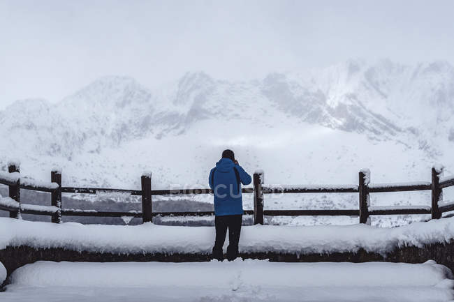 Vista trasera del bosque turístico del hombre cubierto de nieve y hielo en un paisaje brumoso en el norte de las montañas de España - foto de stock
