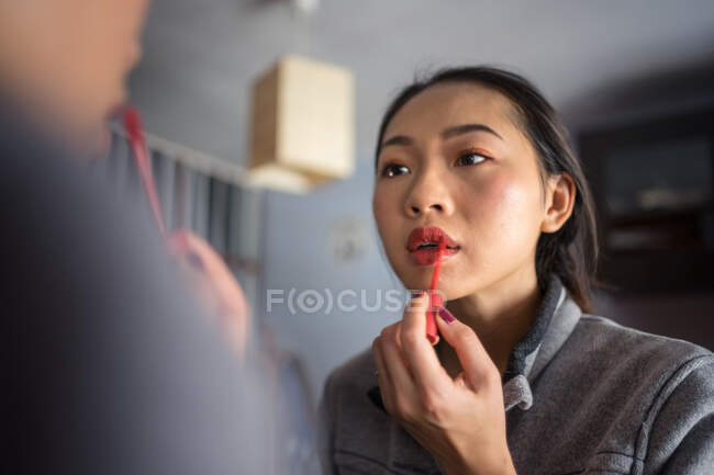 Молодая женщина наносит помаду перед зеркалом — стоковое фото