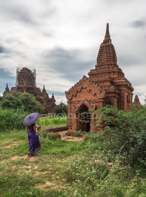 Жінка з парасолькою, що стоїть перед стародавнім храмом — стокове фото
