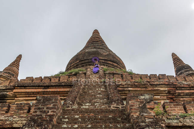 Woman standing on stairs of ancient Buddhist temple — Stock Photo