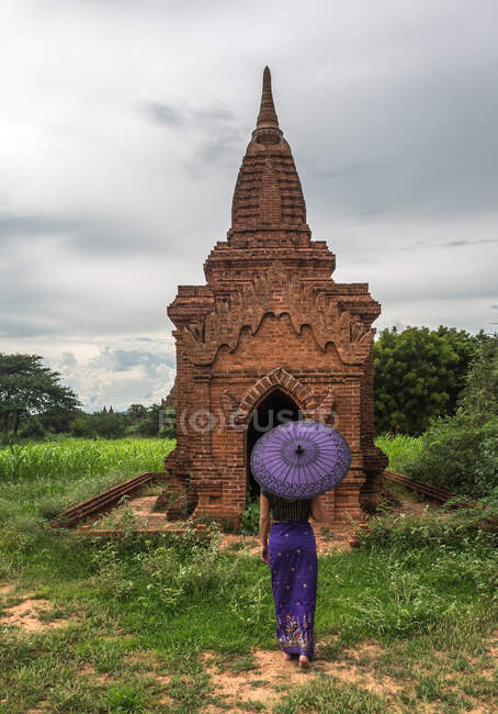 Donna con ombrello in piedi davanti all'antico tempio — Foto stock