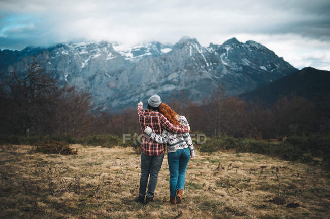 Visão traseira de abraços de casal concurso e ligação em dia frio nas montanhas — Fotografia de Stock