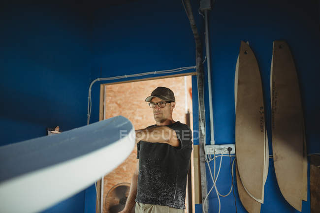 Carpintero haciendo diligentemente tabla de surf en taller - foto de stock