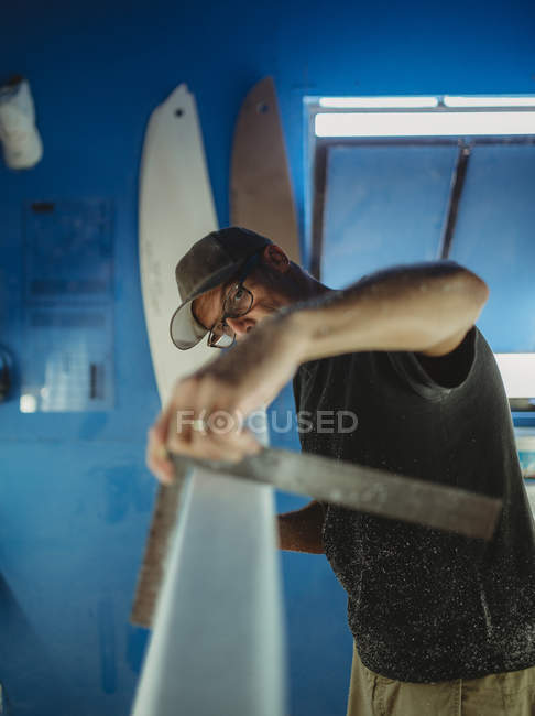 Carpinteiro diligentemente fazendo prancha de surf em oficina — Fotografia de Stock