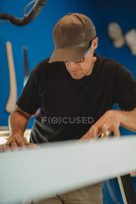 Человек делает доску для серфинга в мастерской — стоковое фото