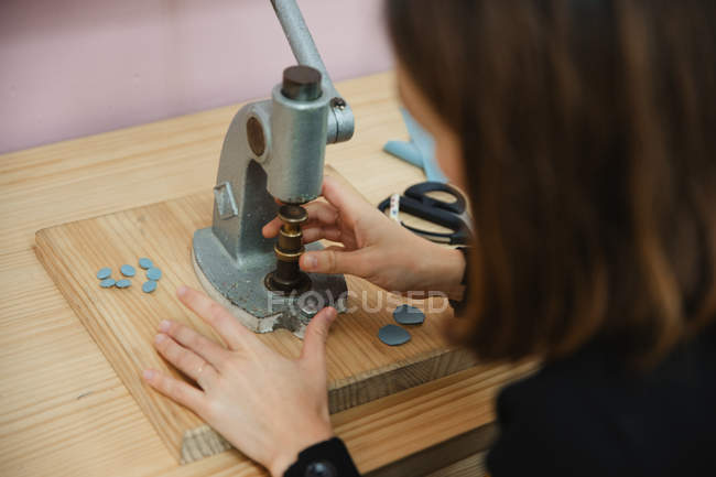 From above of woman using shabby button maker on workbench in tailor studio — Stock Photo