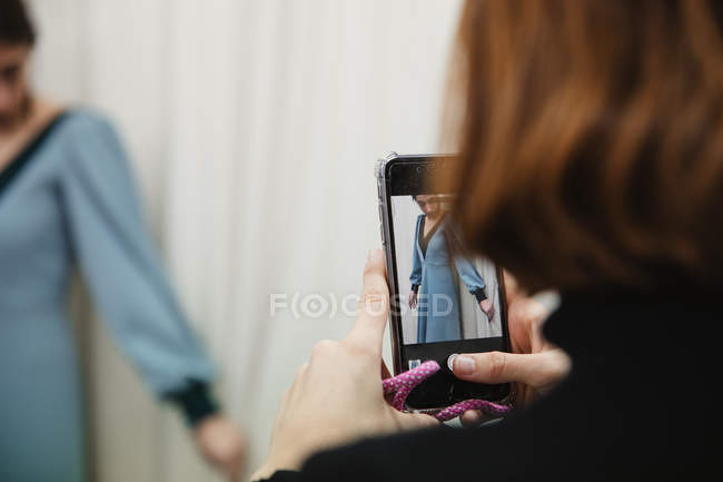 Alfaiate tirar foto do cliente em vestido personalizado para portfólio durante o trabalho em oficina profissional — Fotografia de Stock