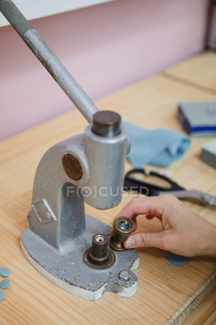 Imagen recortada de la mujer tirando de la palanca del fabricante de botones en la mesa en taller de confección profesional mientras que hace la prenda - foto de stock
