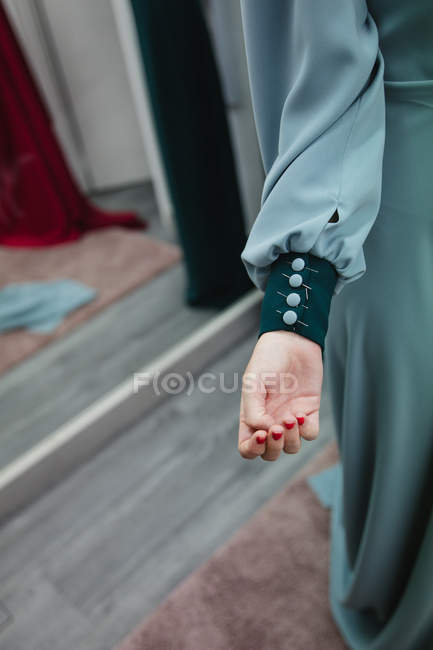 Botones adjuntos con alfileres en la manga de vestido en el brazo modelo en taller profesional - foto de stock