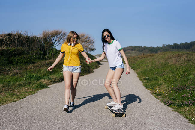 Stylish girlfriends having fun on rural road — Stock Photo