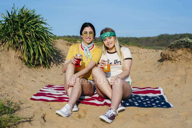 Chicas de moda con bebidas en la playa - foto de stock