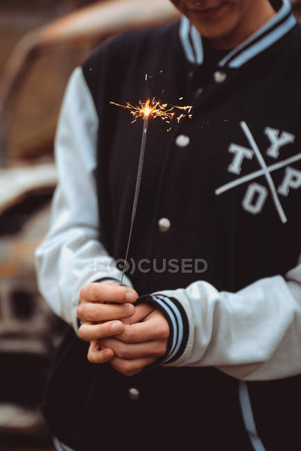 Cropped unrecognizable person holding burning sparkler in countryside — Stock Photo