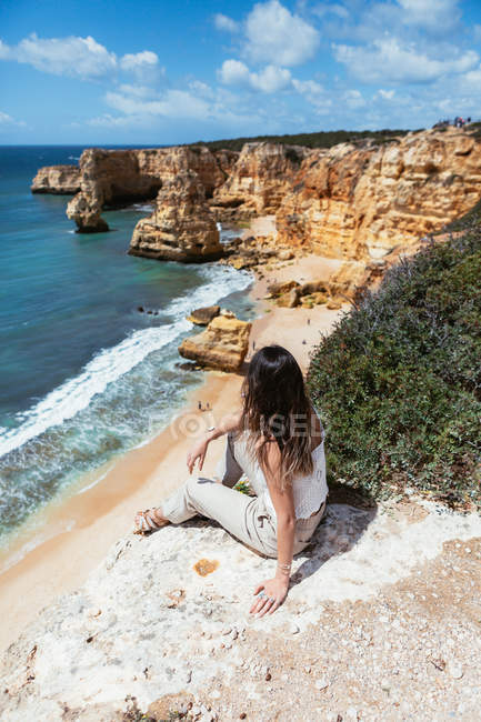 Von oben anonyme Frau sitzt auf Klippe und bewundert winkendes Meer an bewölkten Tag in Portugal — Stockfoto