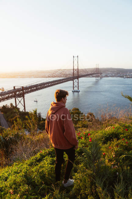 Unrecognizable maschio ammirando ponte sul fiume — Foto stock