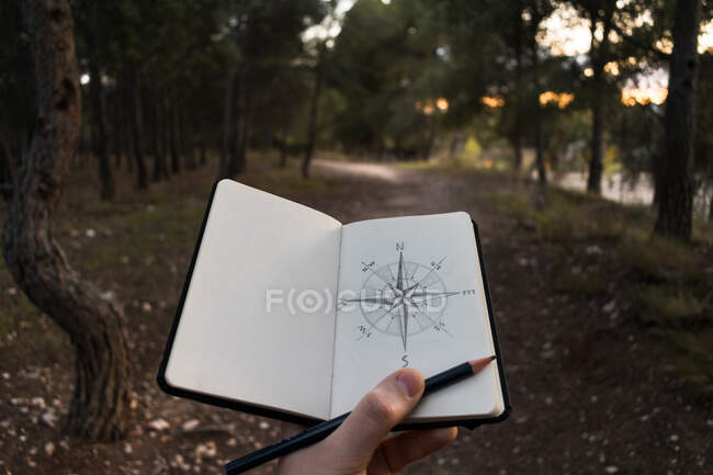 Crop traveler drawing compass on nature — Stock Photo