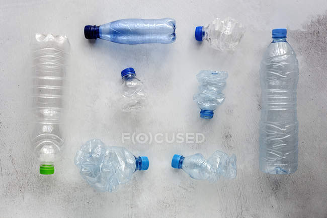 Vista superior de botellas y cajas de plástico dispuestas sobre una superficie de fondo blanco - foto de stock
