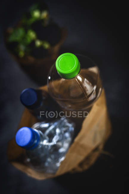 Сверху грязный бумажный мешок с выброшенными пластиковыми бутылками помещен на черном фоне — стоковое фото