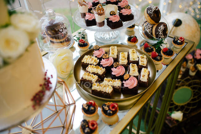 From above sweet delicious creamy chocolate cakes on round tray doughnuts and berry tartlets on festive table in dessert bar in cafe — Stock Photo