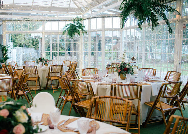 Большой просторный номер с празднично оформленными столами и деревянными стульями под потолком с зелеными растениями — стоковое фото