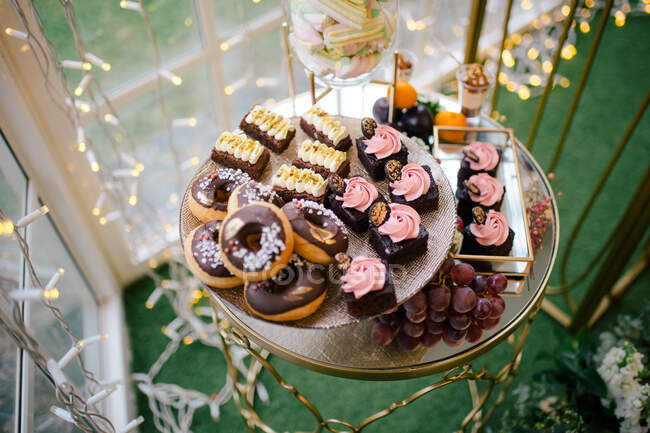 Зверху солодкі смачні вершкові шоколадні торти, прикрашені квітами на скляній підставці в кафе — стокове фото