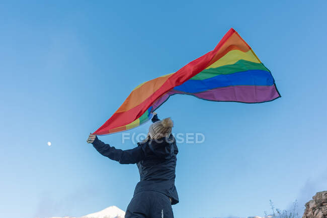 Людина на вершині гори махаючи ЛГБТ прапор — стокове фото