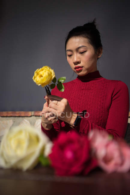 Giovane donna asiatica seduta in negozio e che lavora con le rose — Foto stock