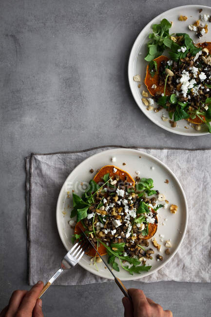 Unbekannter fügt Zutaten zu leckerem gebackenen Süßkartoffelsalat hinzu, während er das Mittagessen über grauem Tisch zubereitet — Stockfoto