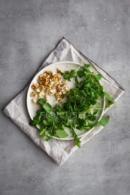 From above plate with assorted nuts and fresh herbs placed on napkin during baked sweet potato salad preparation — Stock Photo