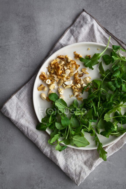 Dall'alto piatto con noci assortite ed erbe fresche poste sul tovagliolo durante la preparazione dell'insalata di patate dolci al forno — Foto stock