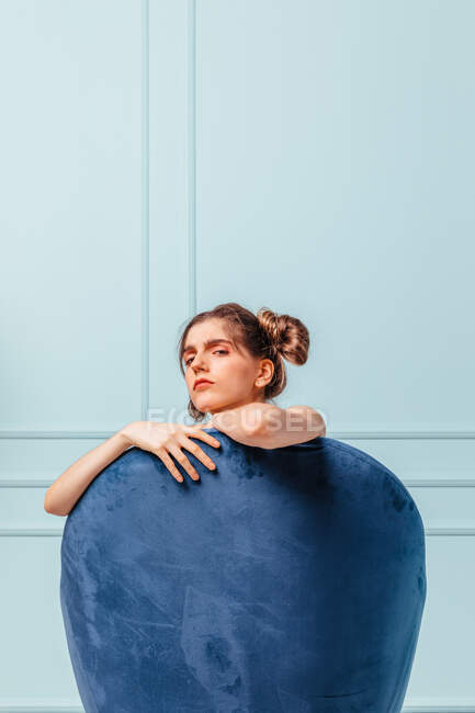 Teen girl mit herausfordernder Geste in einem blauen Sessel auf türkisfarbenem Hintergrund — Stockfoto