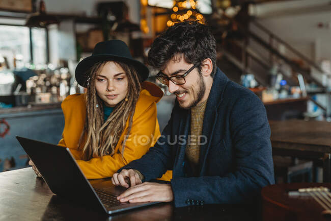 Mujer y hombre con estilo que trabajan en el ordenador portátil en la cafetería - foto de stock