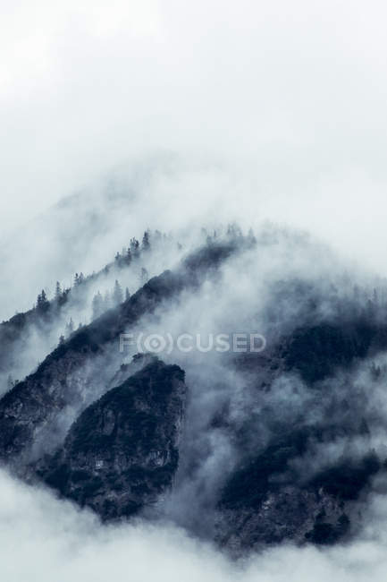 Dramatischer mysteriöser Felsgipfel unter grauen Wolken im Nebel in Österreich — Stockfoto