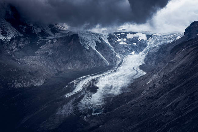 Grigio cielo nuvoloso sopra cresta di montagna grezzo coperto di neve il giorno coperto in Austria — Foto stock