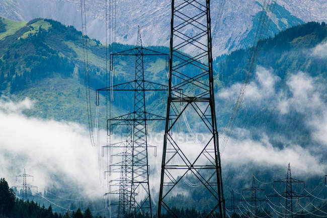 Paisagem industrial de linhas de energia em montanhas pedregosas nebulosas sob nuvens brancas em azul na Áustria — Fotografia de Stock