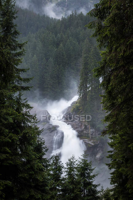 Água limpa caindo de penhasco áspero de dia nebuloso em campos tranquilos na Áustria — Fotografia de Stock