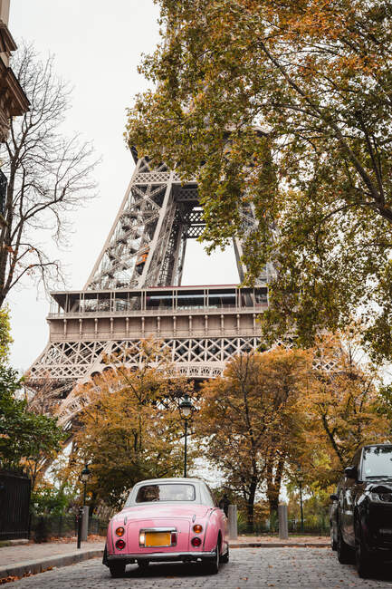 From below Eiffel Tower and pink antique car in street of France in fall — Stock Photo