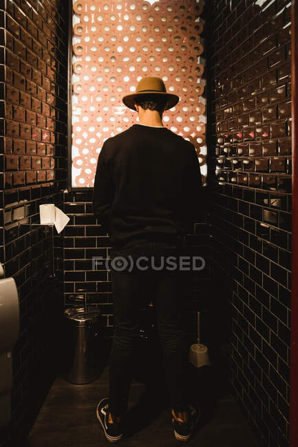 Back view of man peeing in bathroom of cafe in Paris — Stock Photo