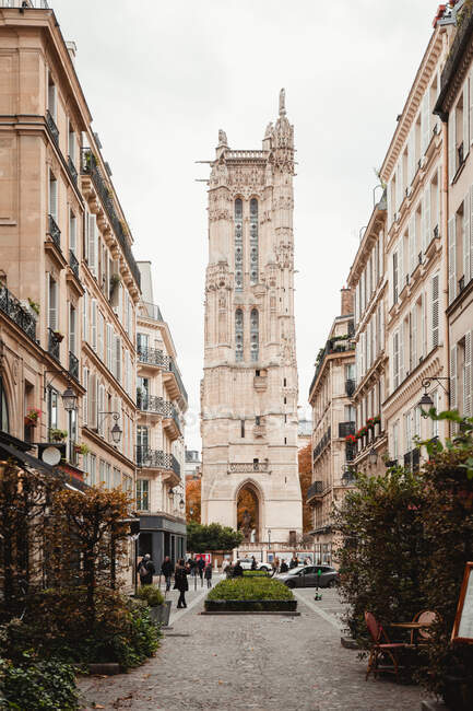 View of aged tower with arch from colorful street of Paris — Stock Photo