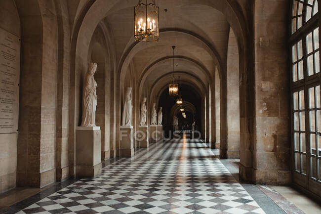 Lungo passaggio di palazzo con scultura e lampadario con candele in Francia — Foto stock