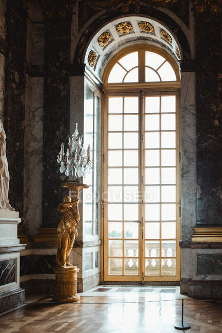 Habitación del castillo con colorida puerta grande y estatua con lámpara en París - foto de stock