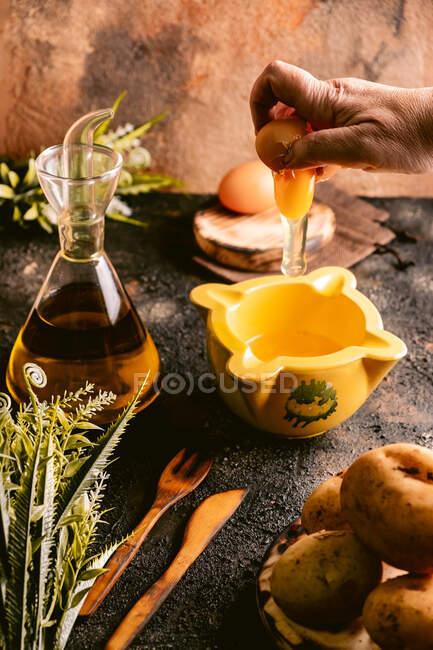 Faceless lady smashing chicken egg in bowl cooking dish of eggs and potatoes in kitchen — Stock Photo