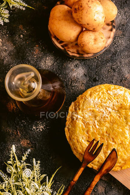 Top view of dish of eggs and potatoes near with pitcher of oil on table in kitchen — Stock Photo