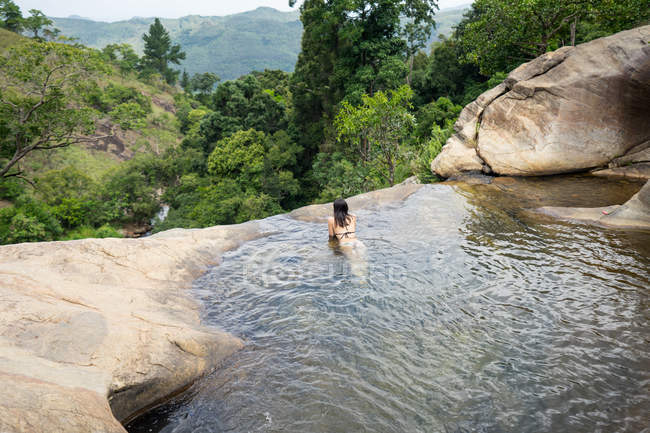 Dall'alto donna rilassata in costume da bagno nuotare in acqua cristallina della cascata di montagna a Diyaluma Falls, Sri Lanka — Foto stock