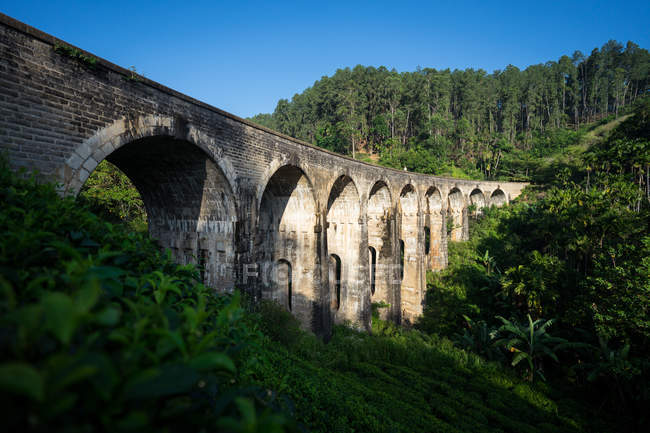 Задумчивая азиатка, идущая по железной дороге по старинному мосту — стоковое фото