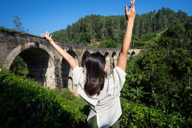 Mujer joven disfrutando del paisaje del puente antiguo - foto de stock