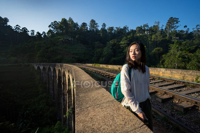 Thoughtful Asian woman walking along railway in old ancient bridge — Stock Photo