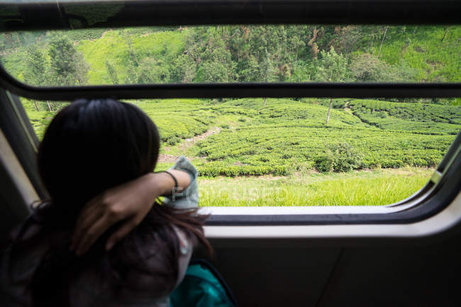 Descansando mulher tomando trem ao longo de plantas verdes — Fotografia de Stock