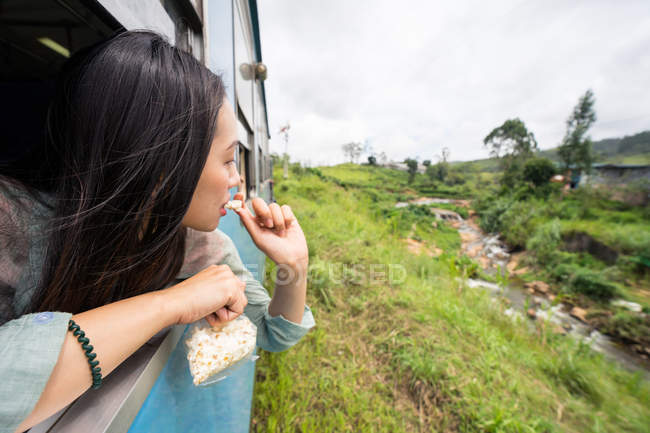 Resting Asian female taking train along green plants — Stock Photo