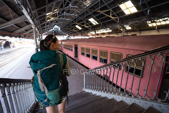 Mujer con mochila en las escaleras en la estación de tren - foto de stock